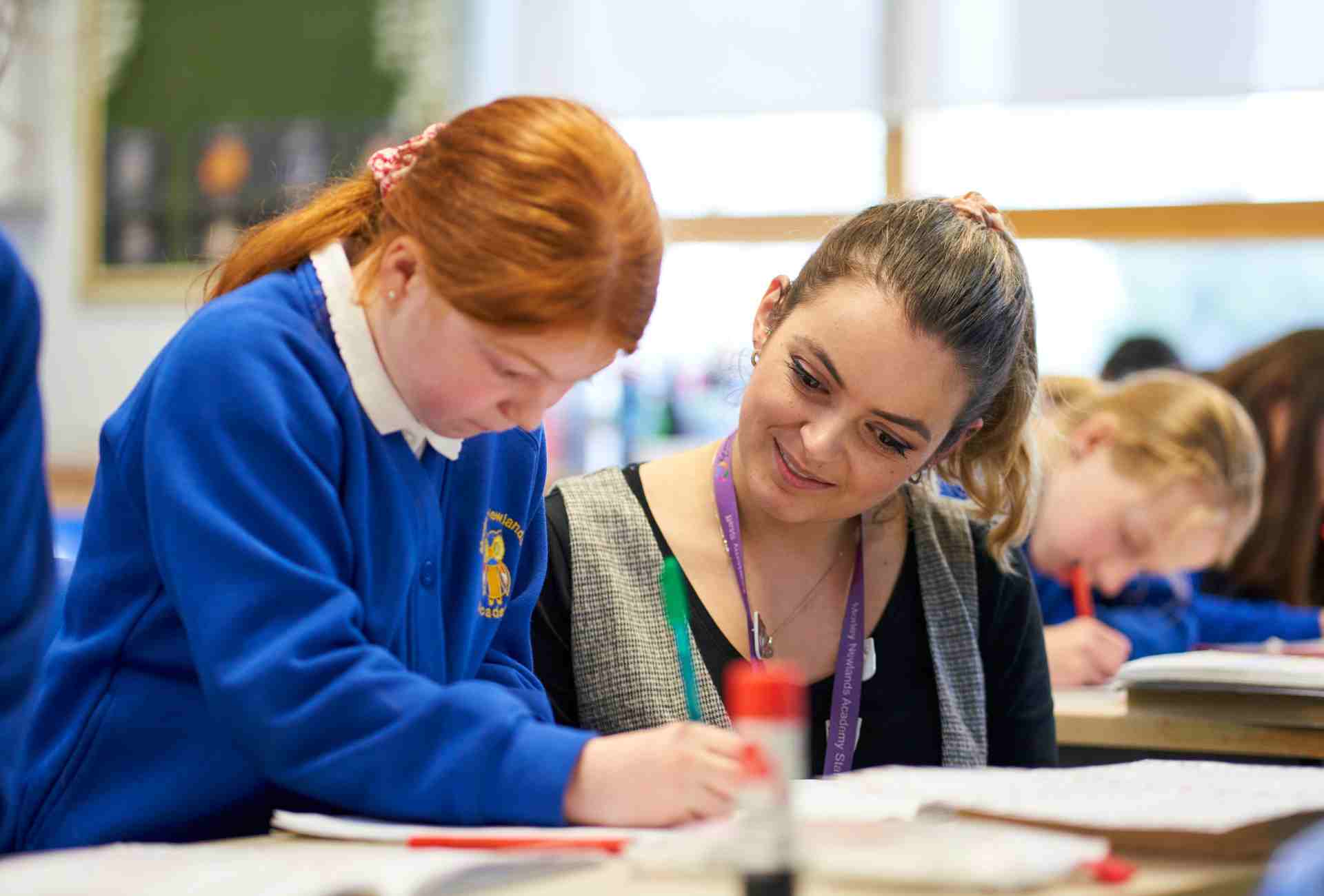 young girl with her teacher writing in a classroom