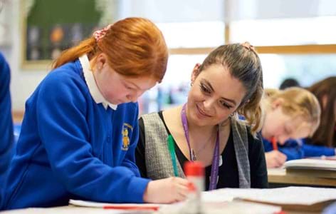 young girl with her teacher writing in a classroom