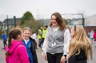 Teacher standing outside with three pupils, listening to what they're saying