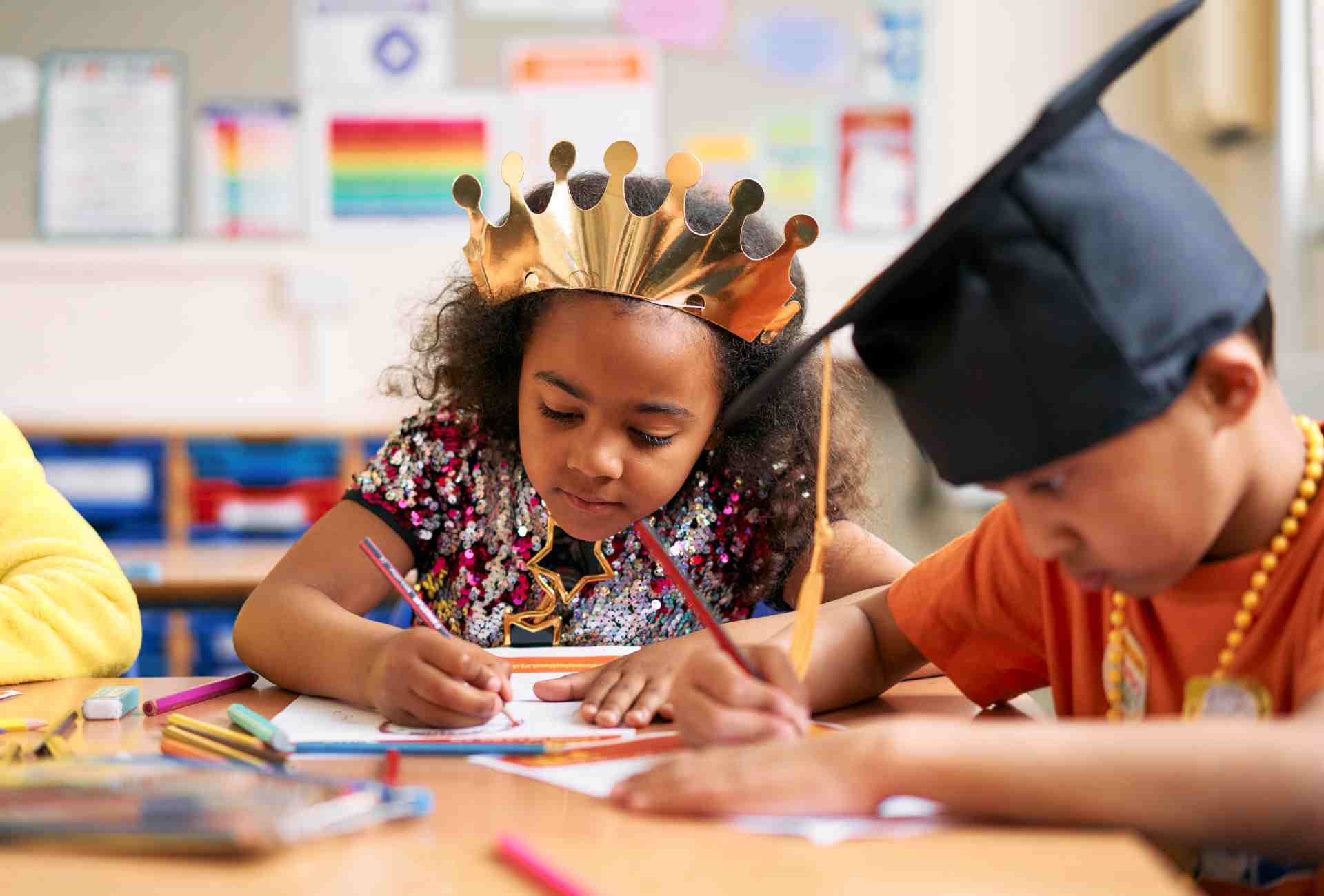 Two young children wearing costumes and engaged in a creative art activity in a classroom.