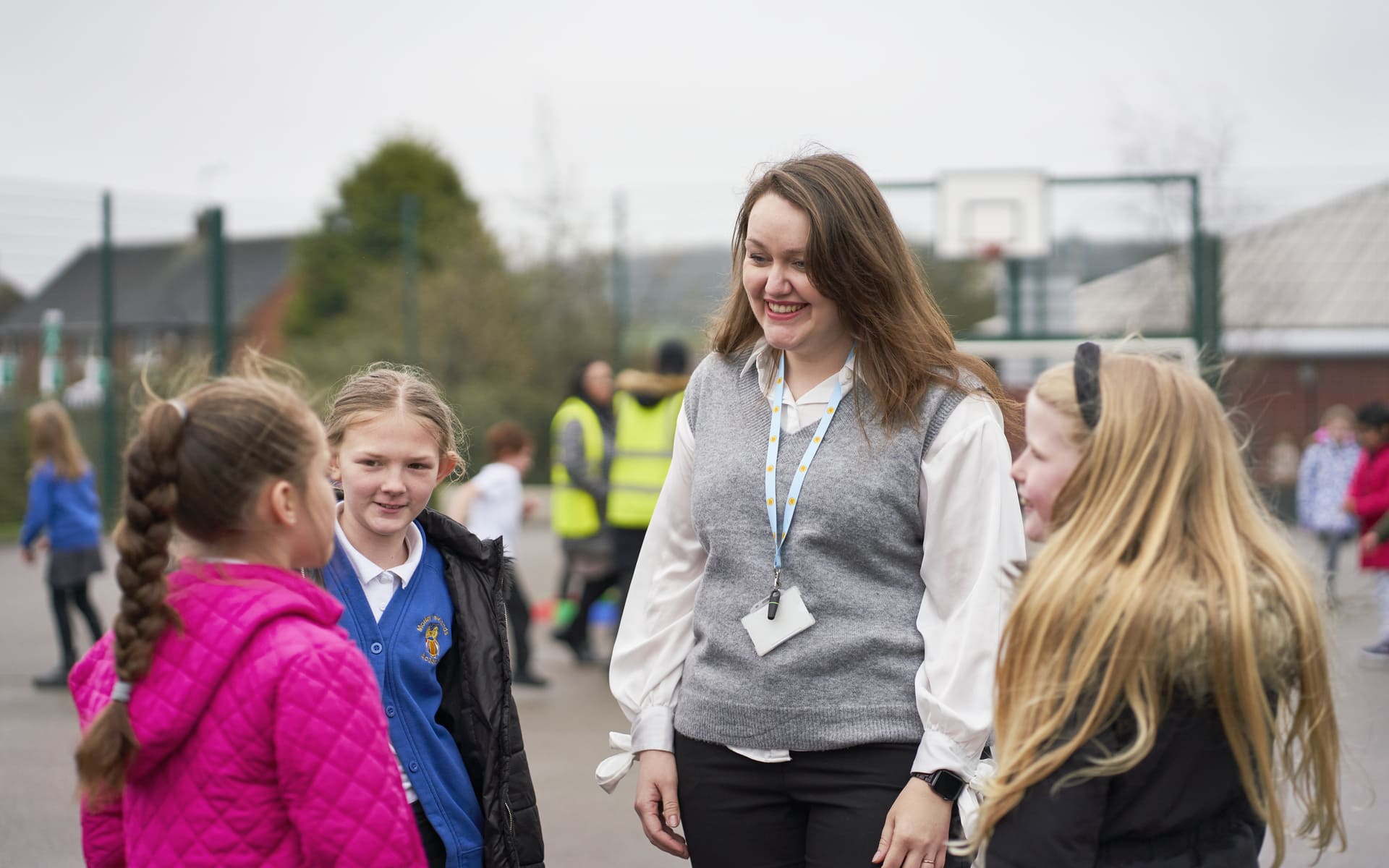 Teacher standing outside with three pupils, listening to what they're saying