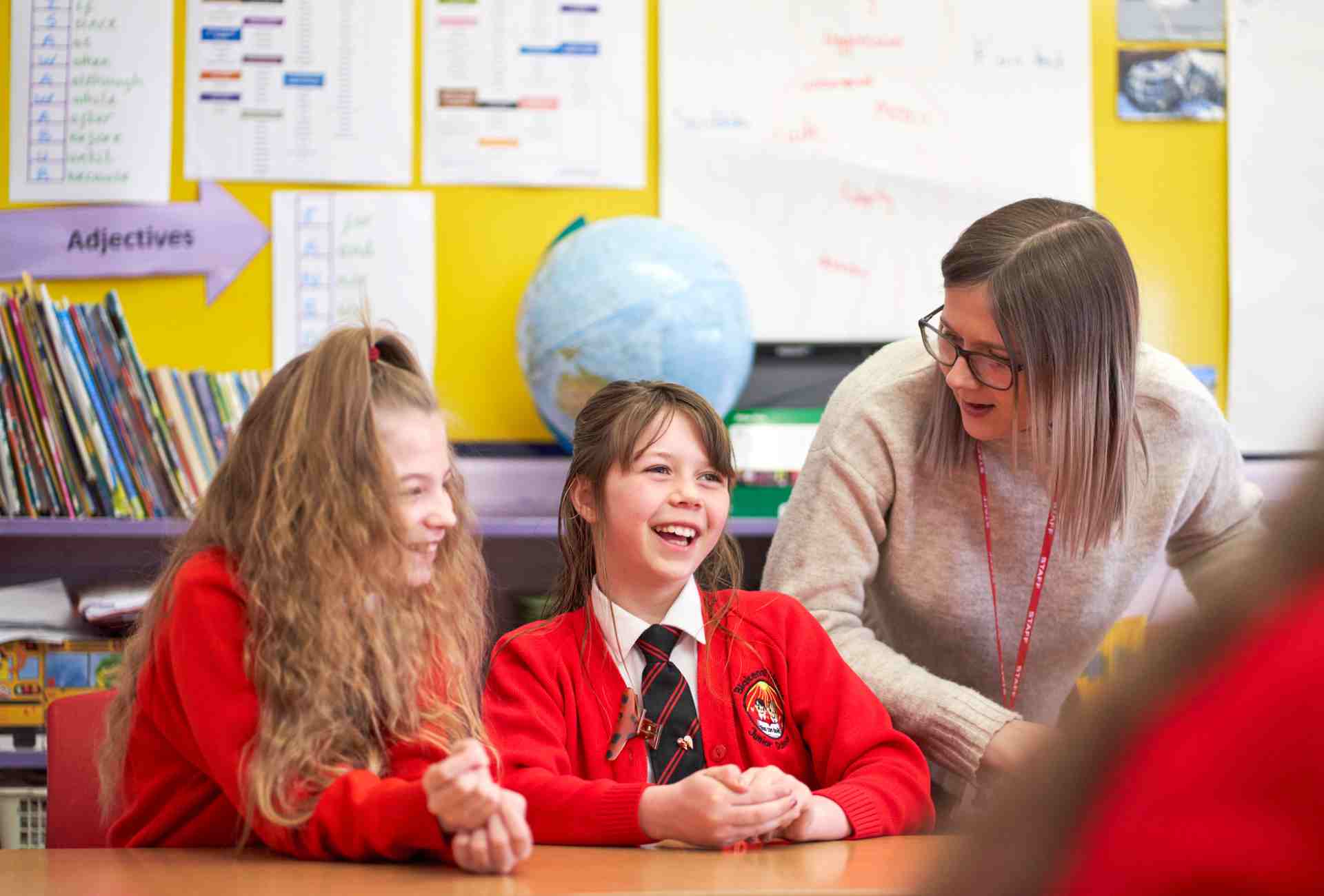teacher talking with two female pupils in a classroom