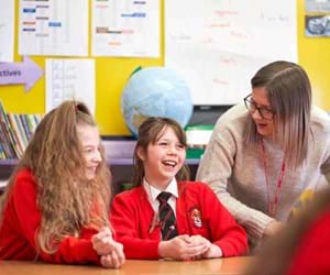 teacher talking with two female pupils in a classroom