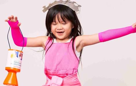 young girl in pink dress with a crown twirling holding a Place2Be donation tin