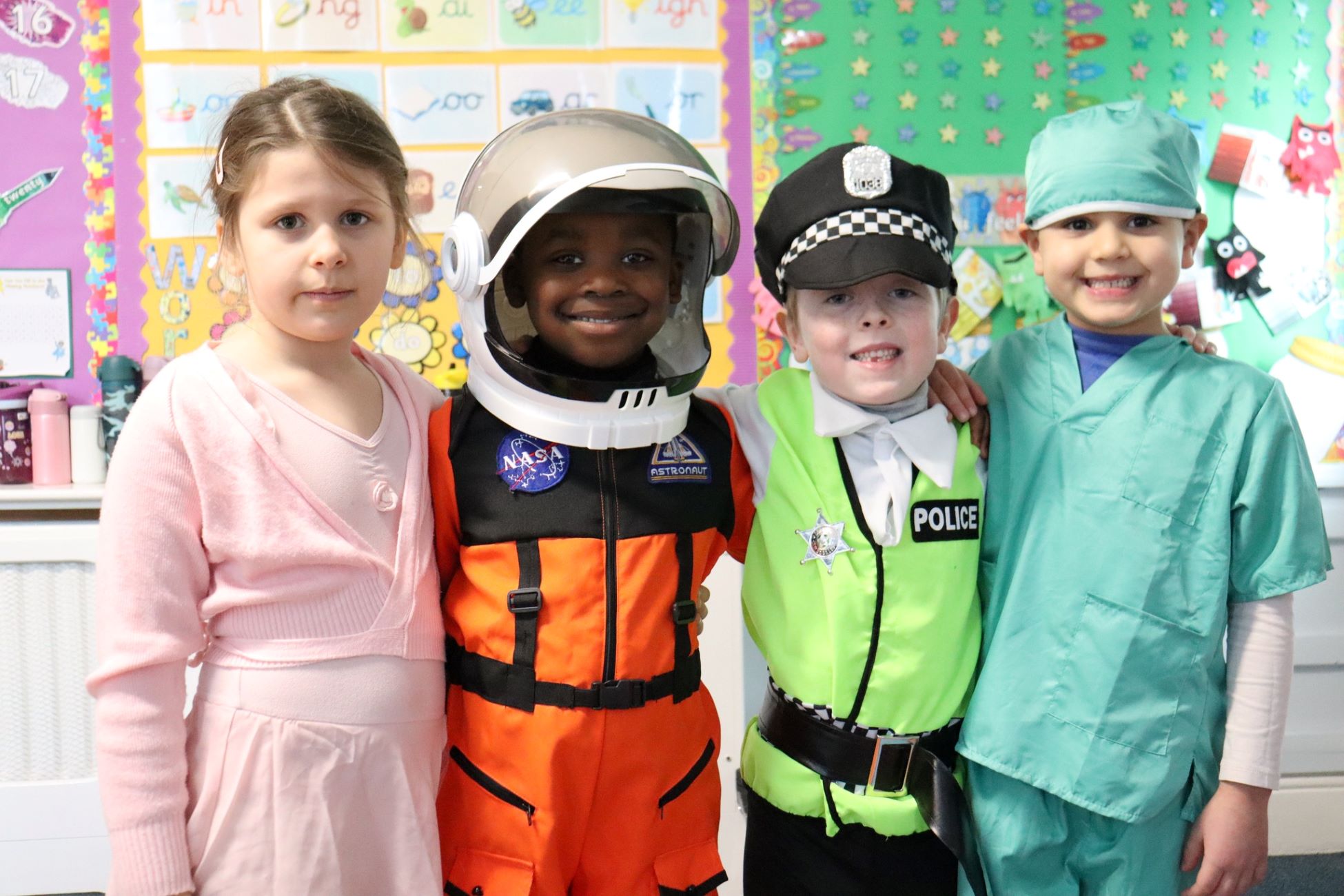 A group of four young children dressed up and smiling at the camera for 2024 Children's Mental Health Week Express Yourself day.