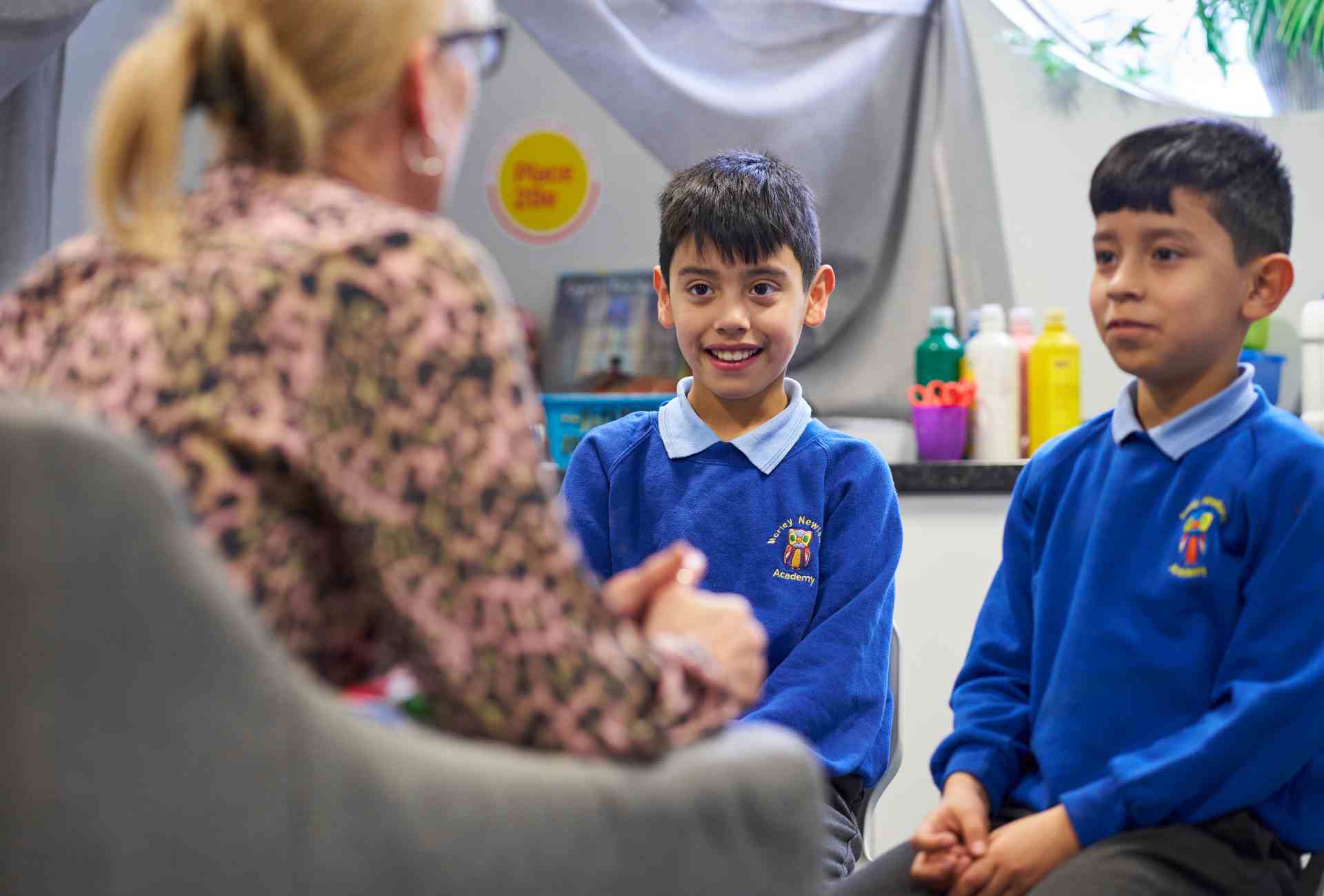 Adult staff member talking to two primary school pupils