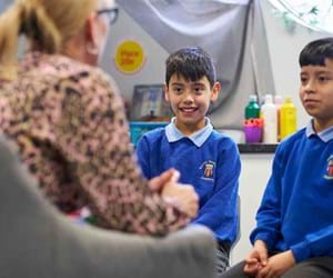 Adult staff member talking to two primary school pupils