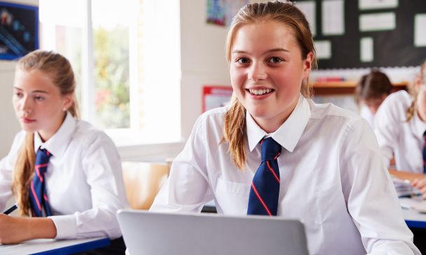 secondary school aged girl sitting in a classroom smiling at the camera