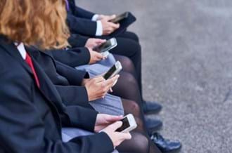 4 young people sat down on their phones