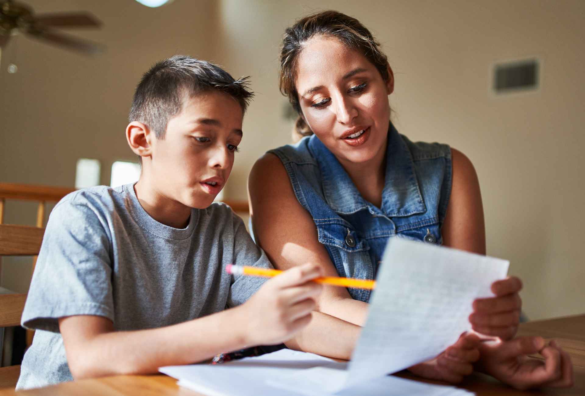 young teenage boy sitting with his mum writing