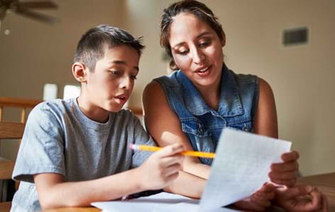 young teenage boy sitting with his mum writing