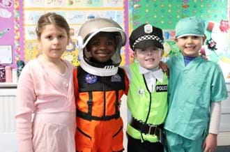 A group of four young children dressed up and smiling at the camera for 2024 Children's Mental Health Week Express Yourself day.